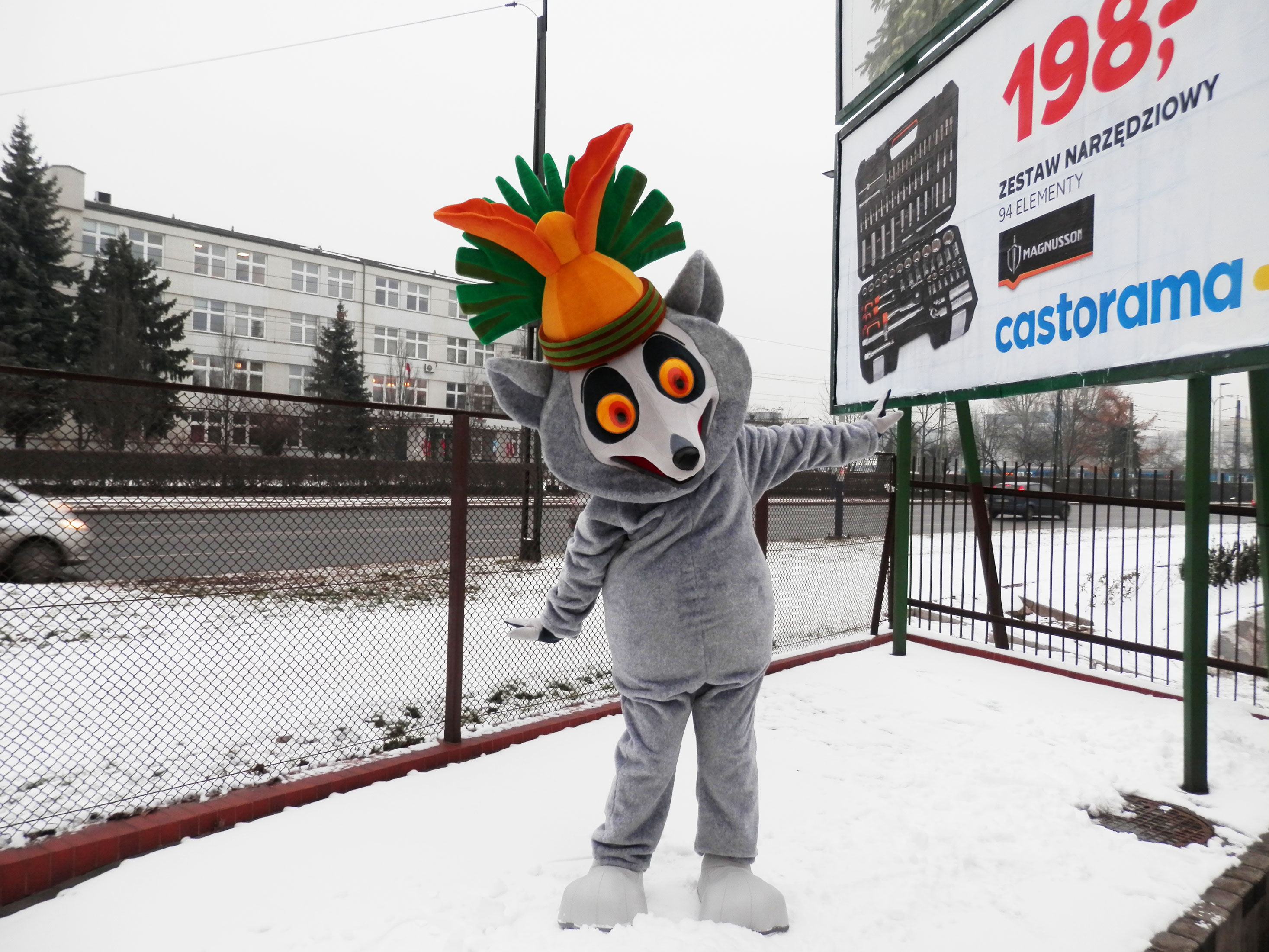 Na fotografii widniej strój reklamowy Lemur wedle koncepcji firmy Elabika, pozujący do zdjęcia przy tablicy reklamowej na jednej z ulic Krakowa
